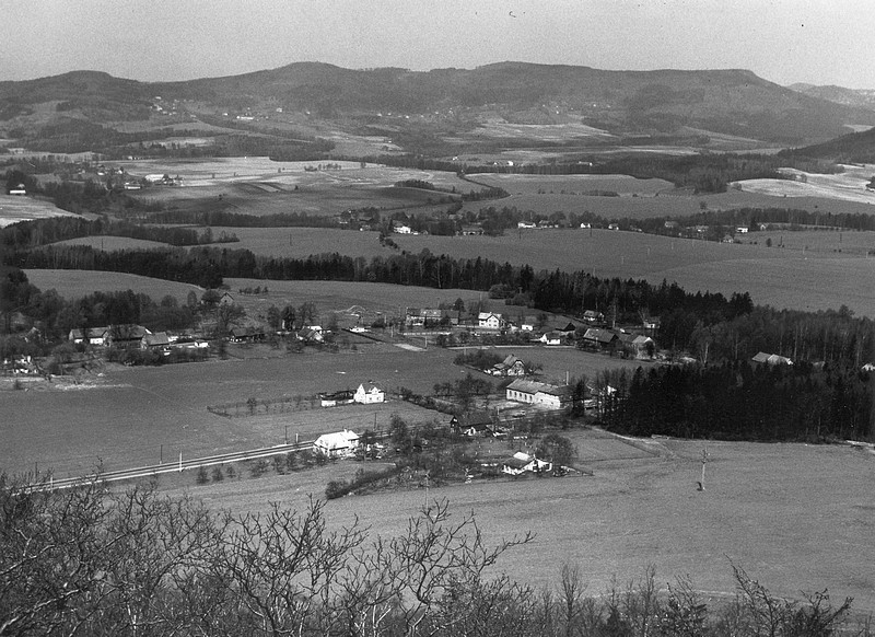 pohled z rozhledny na Špičáku v roce 1980. Jen na druhou stranu, než je město, tedy na Lada. V pozadí Častolovice a úplně vzadu Slunečná. V popředí je u hlavní silnice velký objekt, což je bývalý hostinec Lada s velkým sálem. V 80. letech objekt patřil TJ Nářadí jako motorest, ale už nefungoval a chátral. Poslední pokus o záchranu proběhl převodem vlastnictví do soukromého majetku v roce 1990, ale už bylo pozdě a za nedlouho zmizel takřka 200 let starý zájezdní hostinec zcela. Více info i obrázků, včetně úžasného sálu (archiv Českolipské obrázky)