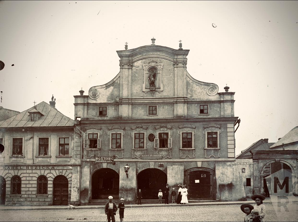 Turnov - náměstí. Dům čp. 94 – hostinec U Zlatého orla. Dům vlastnili na konci 19. století František a Marie Votrubcovi, kteří u překlenutého vjezdu do dvora hostince provozovali řeznický krám. Do podloubí se dvěma oblouky se z náměstí vcházelo po schůdkách, třetí oblouk byl již zastavěn a nacházel se v něm obchod s moukou. V horním štítovém výklenku byl dům osazen sochou svatého Floriána. Zbourán v roce 1906, na jeho místě vystavěna městská spořitelna. Přelom 19. a 20. století, 1896 - 1906 Zdroj: Muzeum Českého ráje v Turnově