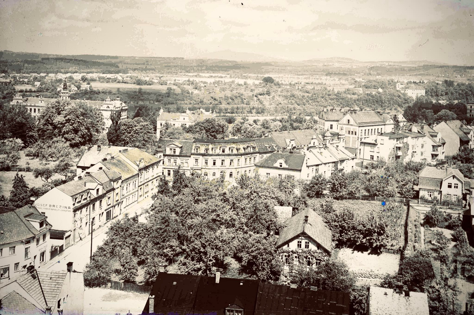 Turnov. Husova ulice pohledem z komína Kobosilovy cihelny. Kněbortova zahrada s domem čp. 1 (podle zvláštního číslování domů na Hruštici, zbourán v roce 1954). Dům čp. 842 – obchod Bohumil Drholec (řezník a uzenář). Dům čp. 645 – obchod Josef Březina (prodej módních dámských a pánských látek). Dům čp. 77 – Hotel Svobody. Turnov 1935. Zdroj: Muzeum Českého ráje v Turnově