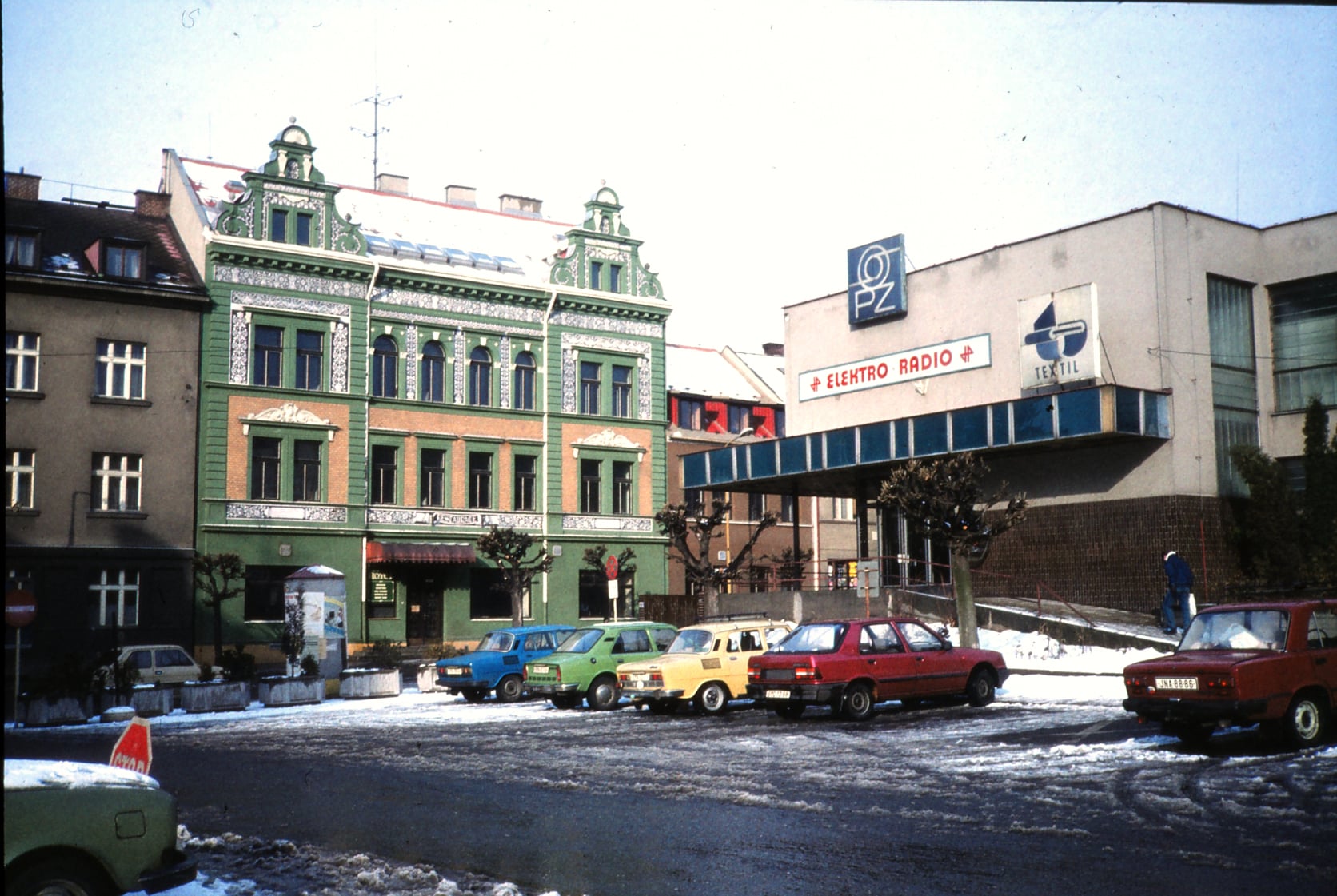 Dnešní historická fotografie 📸 nám předvádí minulost relativně nedávnou, ale přesto již zachycené místo dnes vypadá jinak. Skoro se to ani nezdá, vždyť všechny budovy na fotografii stále stojí a dokonce od té doby nebyly ani přestavěny. Budova hotelu 🏨, ještě donedávna nazývaná "Kleopatra", změnila barvu ze zelené na lososovou. Poněkud krabicovatější budova 🏬 ze sedmdesátých let s obchody sice nezměnila barvu, ale je dnes ověnčena jinými cedulemi. Stáří fotografie prozrazují nejenom budovy, ale i kolekce zaparkovaných aut 🚗 před nimi. Dnes, o 27 let později ⏳, má parkoviště na Havlíčkově náměstí odlišné složení.  zdroj: archiv TPCR