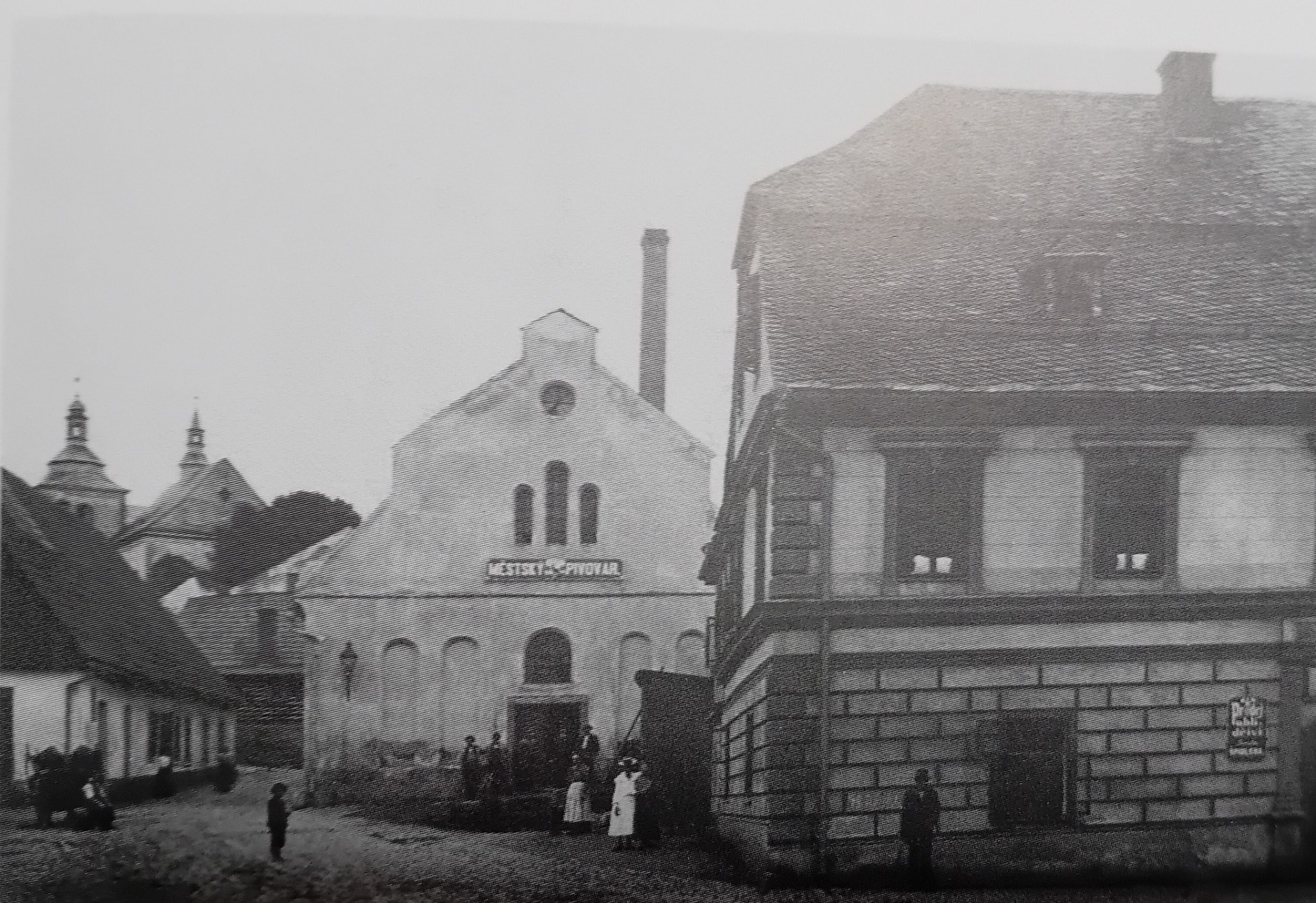 Husova ulice před rokem 1904 , kdy spilka a okolní domy vyhořely ... spilka je tím domem vlevo , uprostřed ... ulice vedla vedle ní , podél pivovaru ... dům nejblíže vpravo postavila tehdejší vrchnost v roce 1691 pro své úředníky a v přízemí byla vrchnostenská hospoda , v pozdějších časech hostinec U koruny České ... vše dokresluje původní barokní kostel z roku 1702 , jenž byl zbořen v roce 1908
