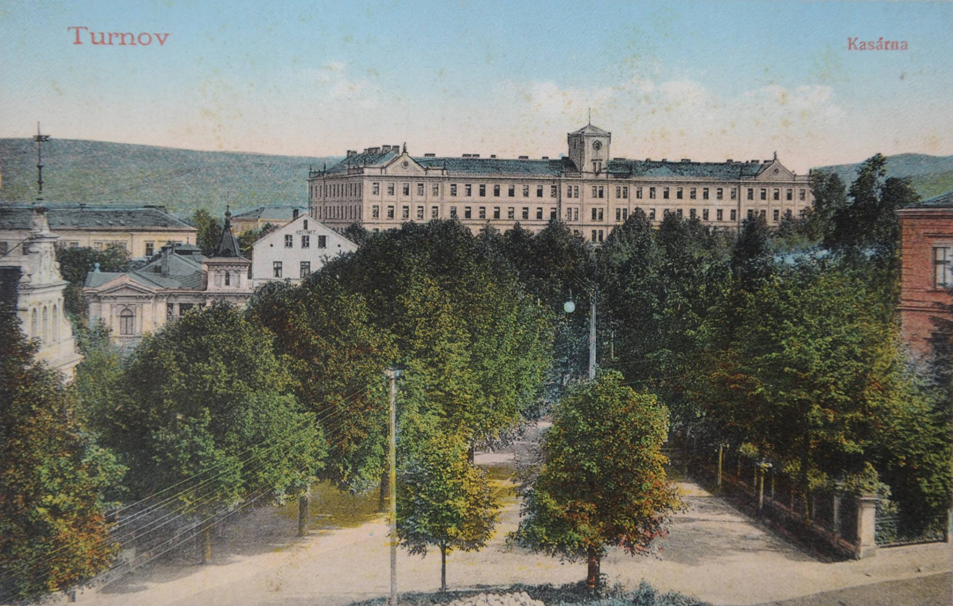 barevná pohlednice z první čtvrtiny 20. století zachycující výhled z budovy střední uměleckoprůmyslové školy. Pohlednici dominuje budova kasáren, v nichž sídlil II. prapor císařského a královského pěšího pluku č. 94 (IR94). Dnes je domovem Hotelové školy a obchodní akademie. Vlevo vyčnívá střecha kasárenské budovy, v níž sídlil III. prapor císařsko-královského zeměbraneckého pěšího pluku č.10 (LIR10). V současnosti tam docházejí žáci III. základní školy. Štít hosince 🛏, který se vlevé části tyčí nad stromy, je přímý předchůdce současného hotelu a restaruace U Karla IV. Před hostincem se nachází Epsteinova vila 🏡 a úplně vlevo u okraje je vidět část vily Šárka. Prostor mezi vilami, dnes obsazen služebnou státní policie, byl tehdy volný. Podobně volný je i prostor na protější straně silnice, kde se nyní nachází Husův sbor ⛪️, v době vzniku pohlednice dosud neexistující. V pravé části nám do výhledu vystupuje roh budovy městské knihovny 📚. náklad pohlednice: Zuna K., Vinohrady Zdroj: archiv Muzea Českého ráje