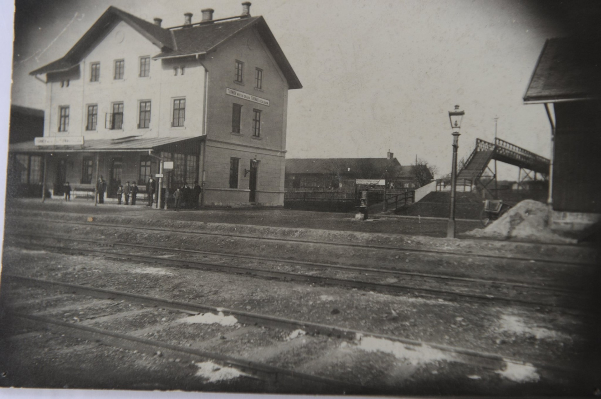 v rámci historické fotografie podíváme na část turnovského hlavního nádraží v první polovině 20. století. Na fotografii je vyobrazena budova nacházející se na druhé straně kolejiště, od níž se vypravovaly vlaky směrem na Jičín. S hlavní nádražní budovou byla spojena mostkem, který vedl přes koleje a umožnoval tak nerušený průchod cestujících. 🚂🚂🚂 Zdroj: Muzeum Českého ráje v Turnově