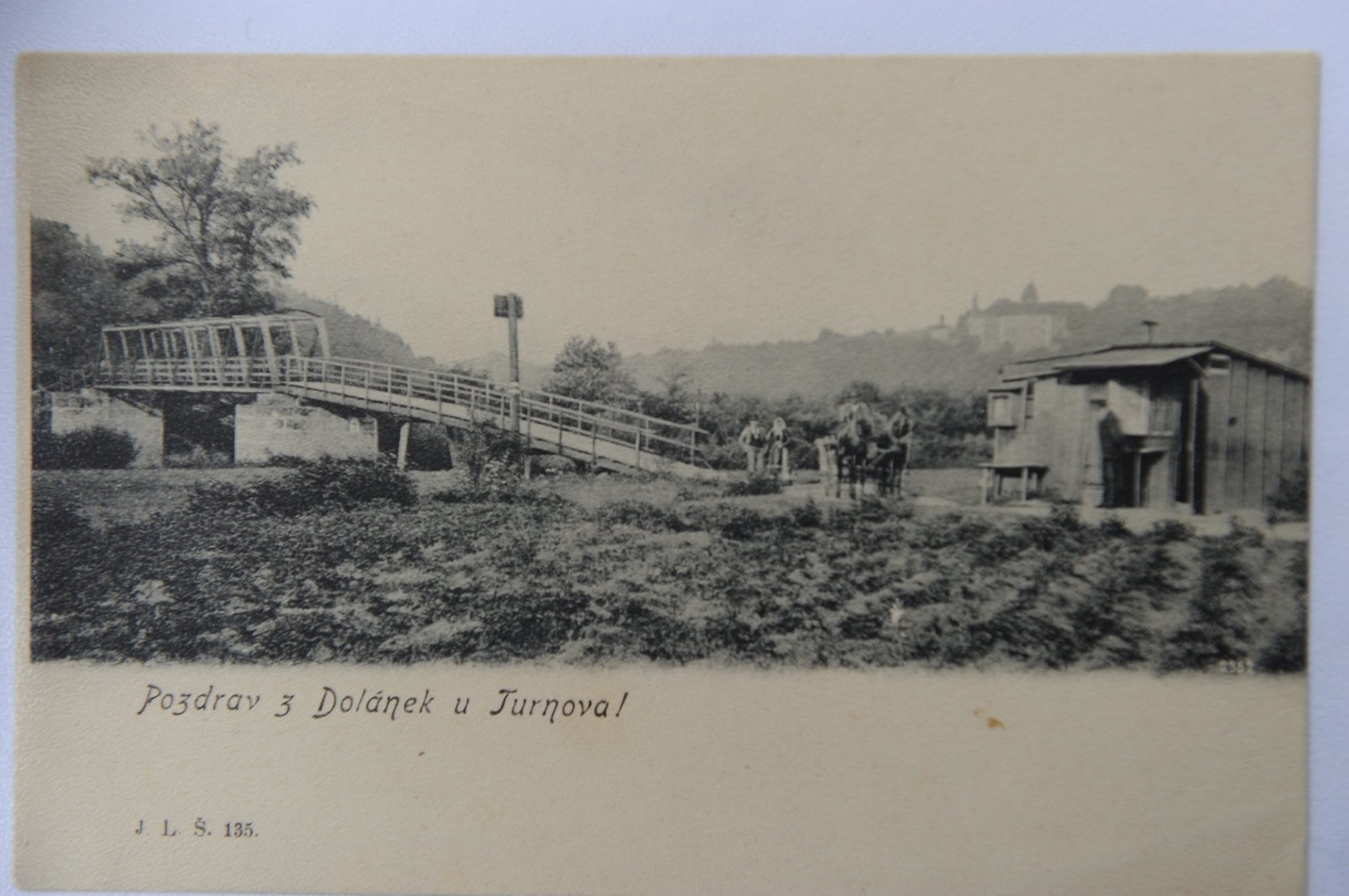 Pozdrav z Dolánek u Turnova z konce 19. století. Na snímku je zachycen most přes Jizeru, u kterého se nacházel stánek s občerstvením a v pozadí zámek Hrubý Rohozec. Náklad: J. L. Š. Zdroj: Muzeum Českého ráje v Turnově