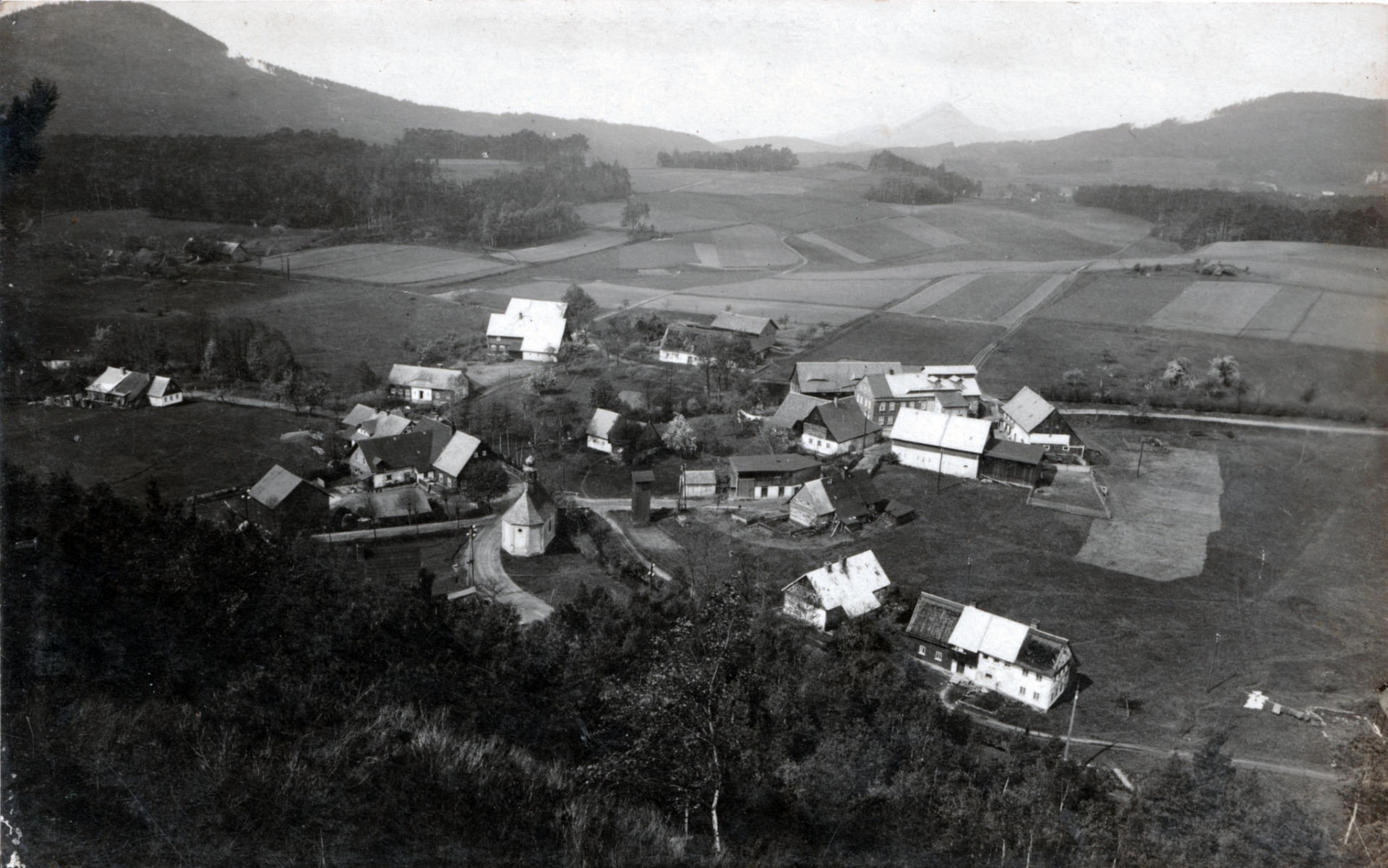Vesnicí na pohlednici je bezesporu Klein Mergthal (Mařeničky). Vlevo je Grünberg (Zelený vrch) u Zwickau i.B. (Cvikov), uprostřed na obzoru výrazný kužel Kleisu (Klíč) a vpravo Glasertberg (Trávnický vrch). Fotografie byla pořízena ze Stiefelbergu (Bota). (archiv Radim Nejedlý - komentář Stefan Hornig)