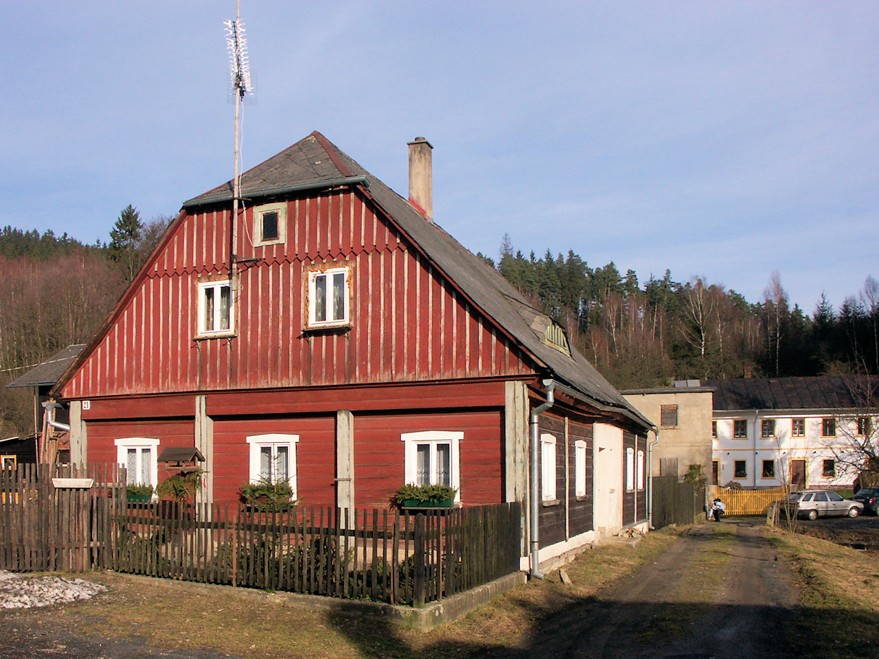 Rousínov Roubený dům uprostřed osady. V pozadí je vidět bývalý mlýn. Foto: Jiří Kühn.