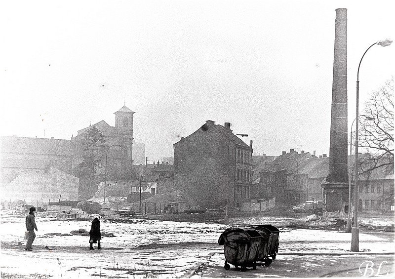 Únor 1986 z lázní zbývá komín - . Dnes je tu zastávka autobusu u Banca. Uprostřed snímku ještě původní hotel Pošta, stará pošta, odborový dům, restaurace U Stadionu a vše ostatní, co v tom domě bylo. Dnes je na tom místě novostavba o menší hmotě. V popředí parkoviště u zásobování Banca vedle vjezdu na parkoviště. (autor příspěvku Českolipské obrázky)
