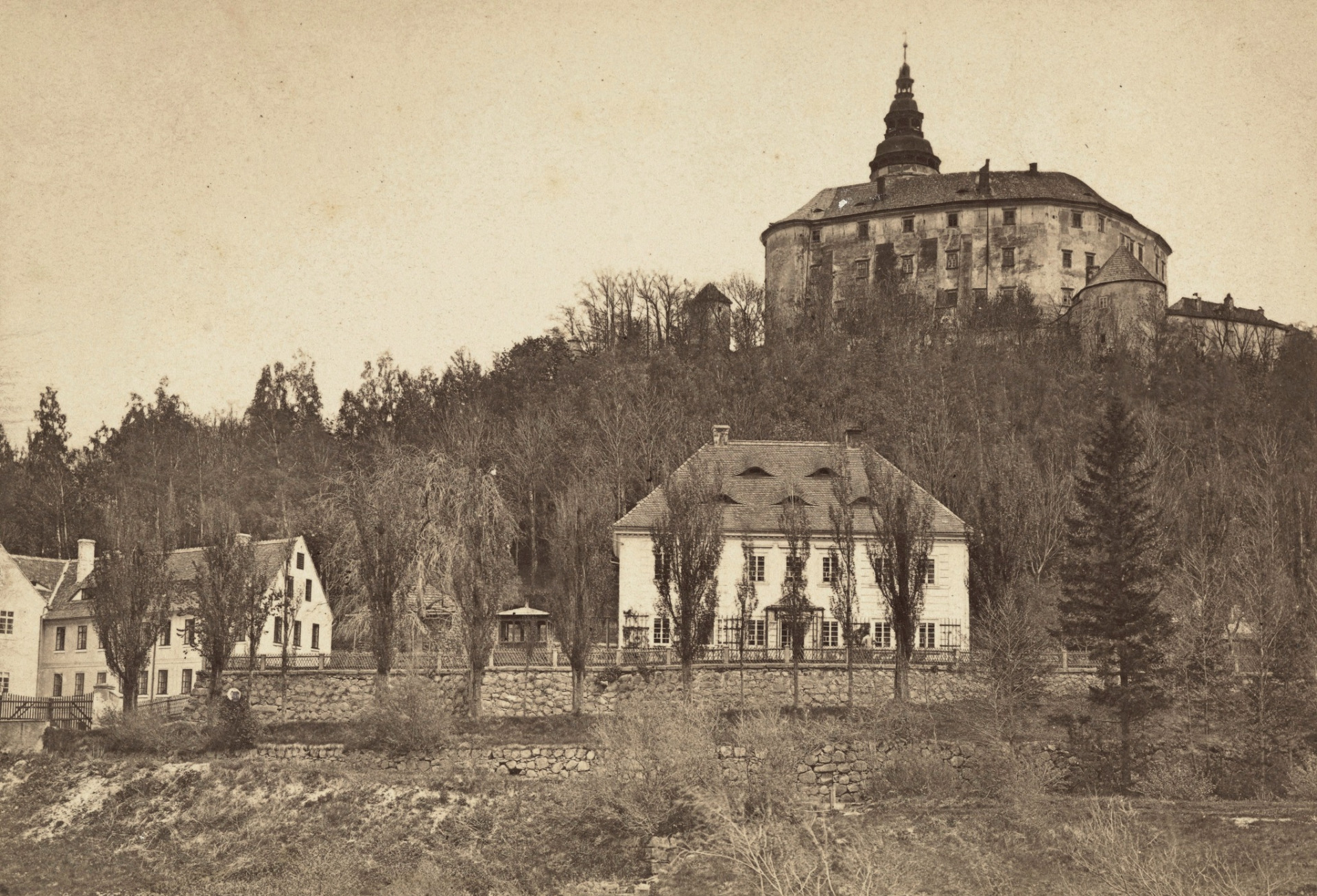 Frýdlant -1878 Vzácný historický záběr z roku 1878. V popředí, pod zámeckým kopcem, je zachycena tehdejší podzámčí zástavba včetně klasicistního měšťanského domu se zahradou a původním oplocením. Snímek pochází z dílny renomovaného fotografa Roberta Halma (1828-1910). Halm patřil v druhé polovině 19. století k průkopníkům krajinářské a místopisné fotografie v oblasti Jizerských hor a Krkonoš. (archiv J.Peterka)